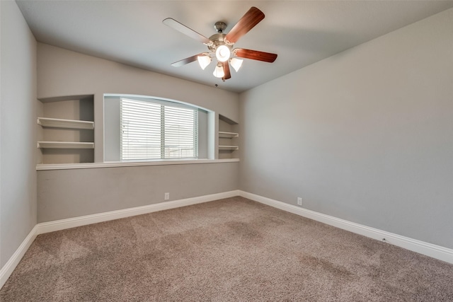 carpeted empty room with ceiling fan and built in shelves