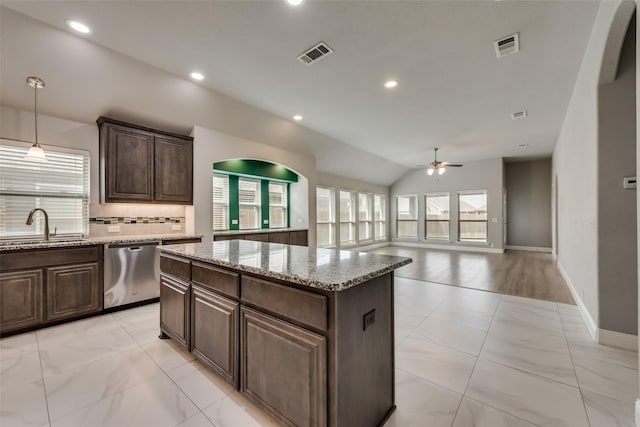 kitchen with dark brown cabinetry, sink, stainless steel dishwasher, a kitchen island, and backsplash