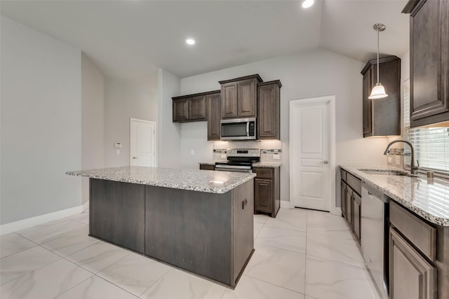 kitchen featuring sink, appliances with stainless steel finishes, decorative backsplash, a kitchen island, and decorative light fixtures