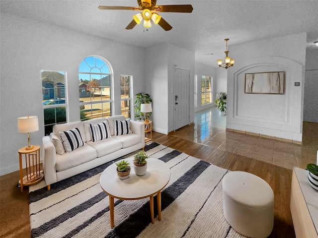 living room featuring dark hardwood / wood-style floors, ceiling fan with notable chandelier, and a textured ceiling