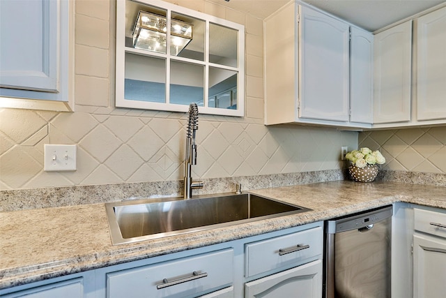 kitchen with tasteful backsplash, sink, stainless steel dishwasher, and white cabinets