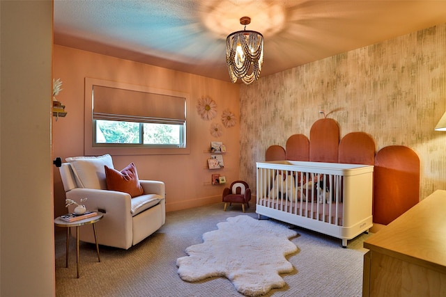 bedroom featuring a crib, carpet, and an inviting chandelier