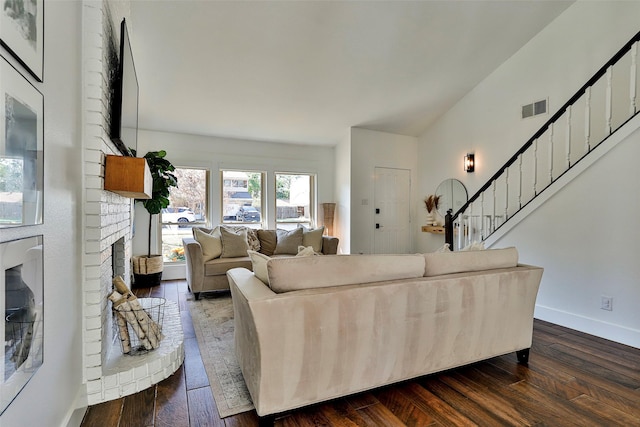 living room featuring dark hardwood / wood-style flooring, a brick fireplace, and vaulted ceiling