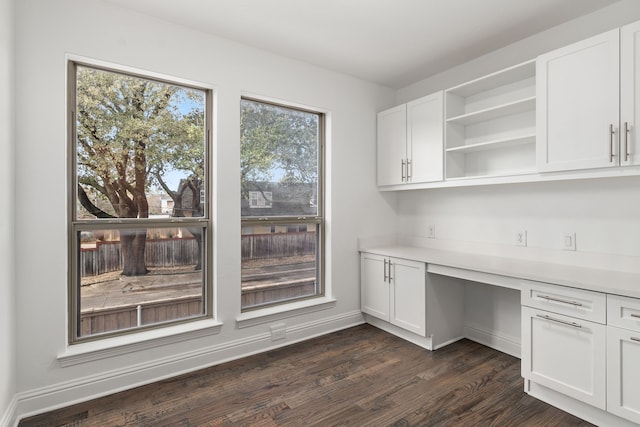 unfurnished office with dark hardwood / wood-style flooring and built in desk