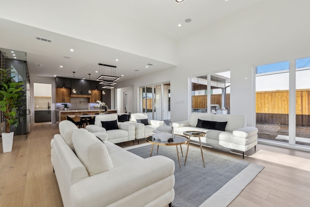 living room featuring a towering ceiling and light hardwood / wood-style flooring