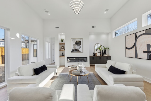 living room featuring a towering ceiling and light hardwood / wood-style floors