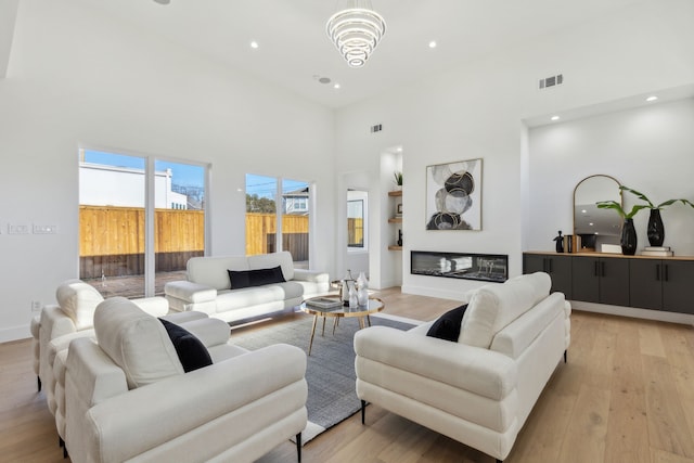 living room featuring a towering ceiling and light hardwood / wood-style flooring