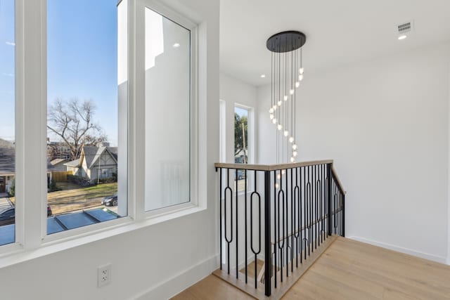 corridor featuring an inviting chandelier and light wood-type flooring