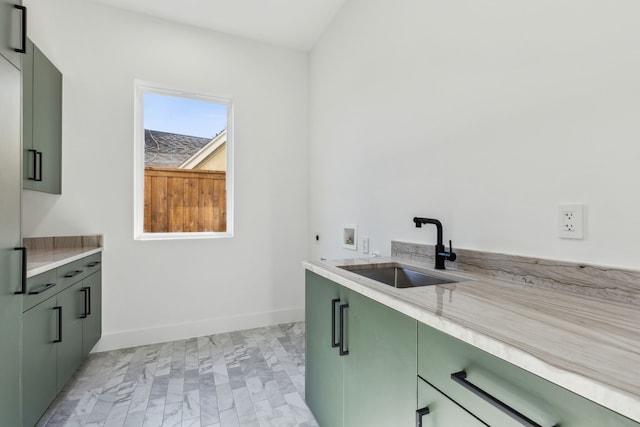 kitchen featuring green cabinets, light stone countertops, and sink