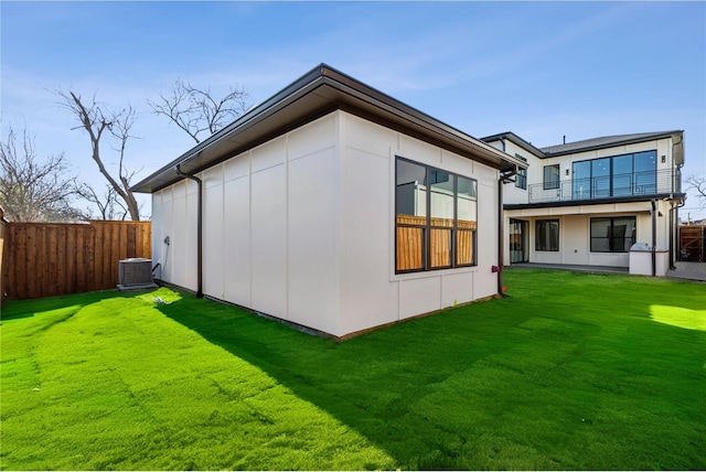 rear view of house featuring cooling unit and a lawn