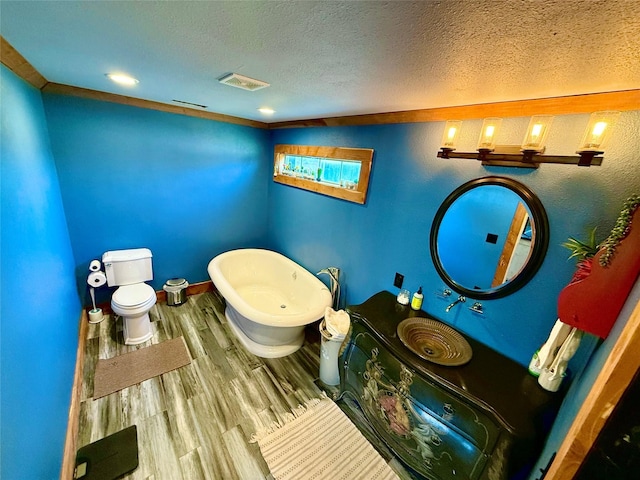 bathroom with wood-type flooring, toilet, a textured ceiling, and a washtub