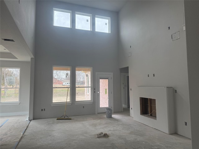 unfurnished living room featuring a towering ceiling