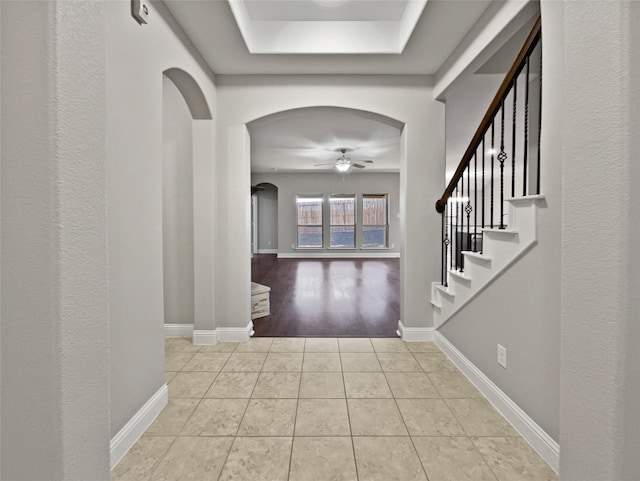 entryway featuring light tile patterned floors, a tray ceiling, and ceiling fan