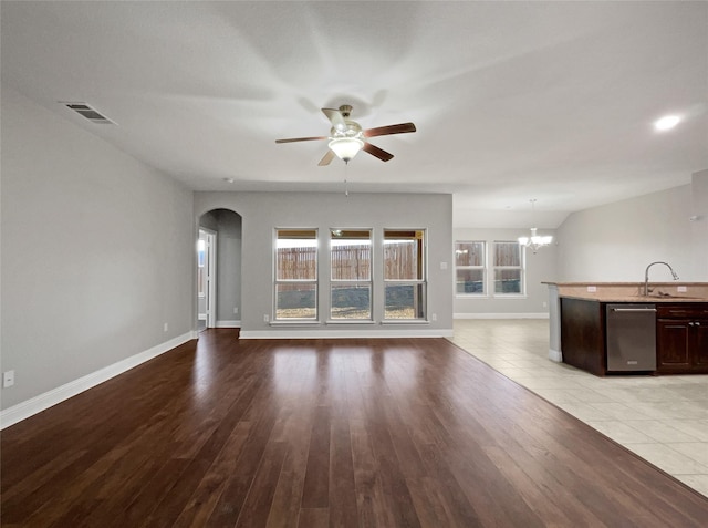 unfurnished living room featuring sink, ceiling fan with notable chandelier, and light hardwood / wood-style floors