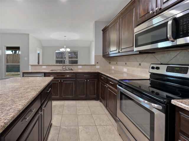 kitchen with pendant lighting, sink, backsplash, stainless steel appliances, and dark brown cabinets