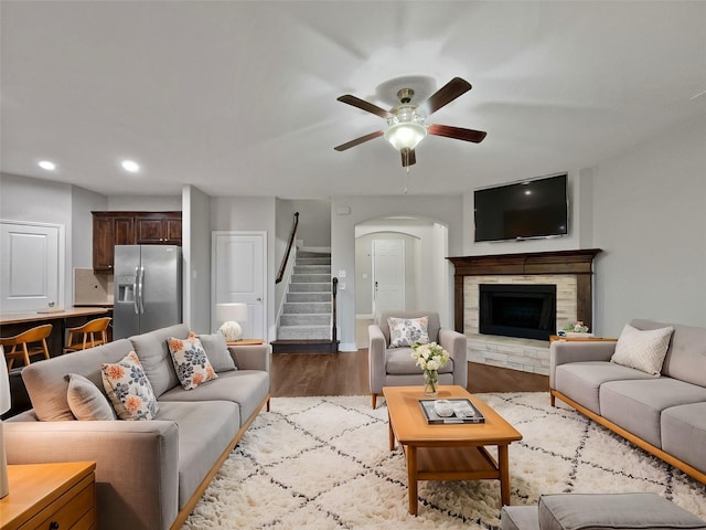 living room featuring ceiling fan, wood-type flooring, and a fireplace