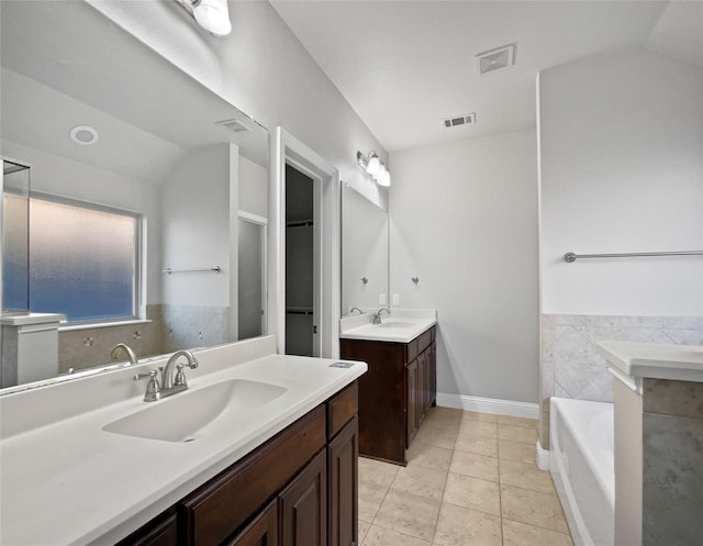 bathroom with vanity, lofted ceiling, tile patterned floors, and a bathtub