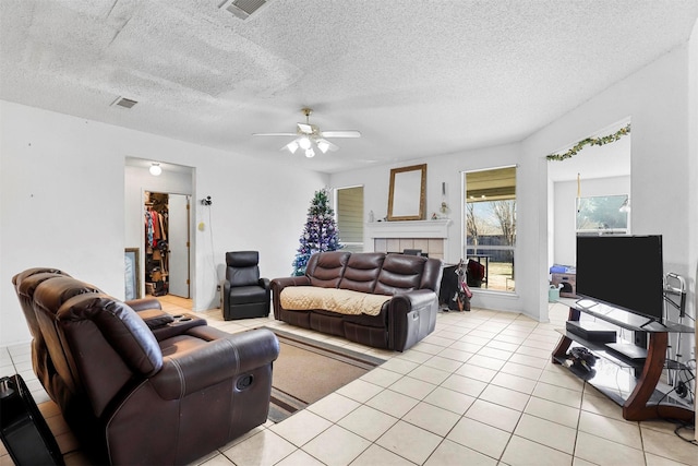 living room with ceiling fan, a textured ceiling, and light tile patterned floors