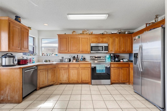 kitchen with light tile patterned flooring, appliances with stainless steel finishes, and a textured ceiling