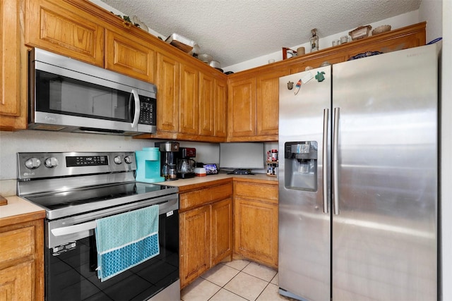 kitchen with light tile patterned flooring, appliances with stainless steel finishes, and a textured ceiling