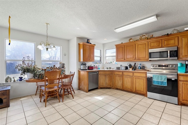 kitchen featuring pendant lighting, a notable chandelier, stainless steel appliances, and light tile patterned flooring