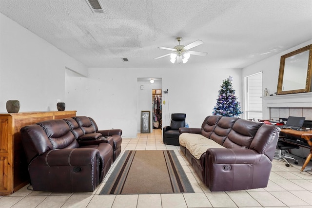 living room featuring light tile patterned flooring, ceiling fan, and a textured ceiling