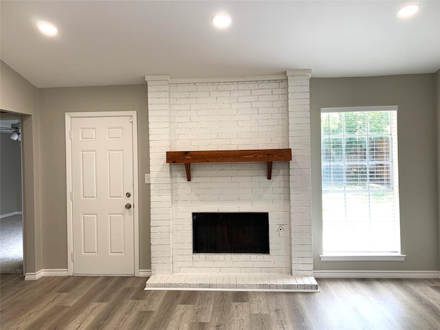 unfurnished living room featuring a brick fireplace and wood-type flooring