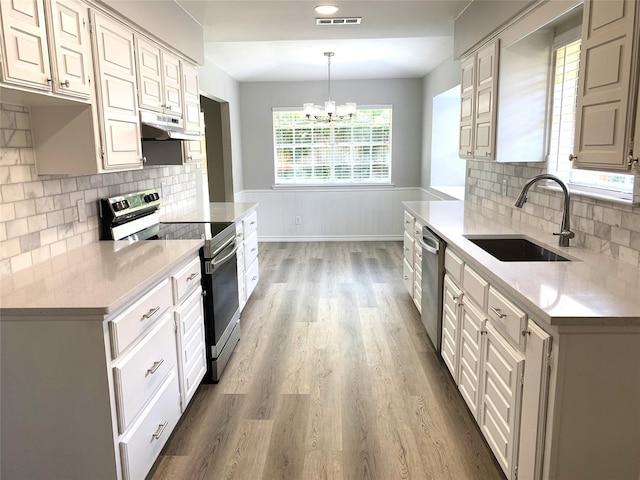 kitchen with pendant lighting, sink, wood-type flooring, and stainless steel appliances