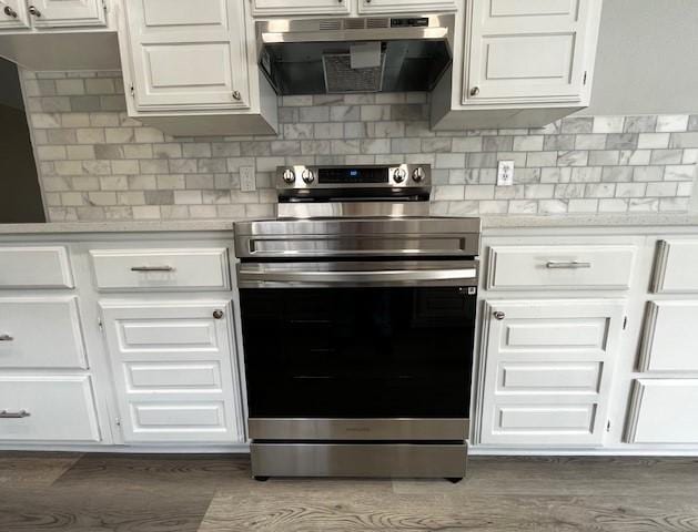 kitchen featuring white cabinetry, decorative backsplash, dark hardwood / wood-style floors, and stainless steel electric range