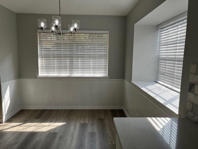 unfurnished dining area with dark wood-type flooring and an inviting chandelier