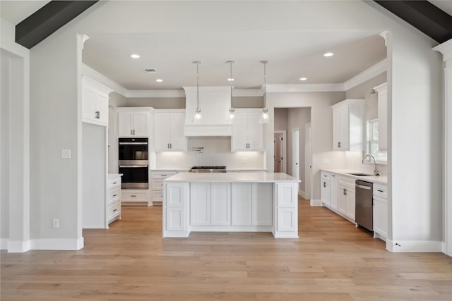 kitchen featuring appliances with stainless steel finishes, sink, a kitchen island, and white cabinets