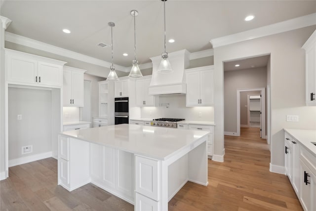 kitchen with pendant lighting, white cabinetry, stainless steel gas cooktop, a center island, and light wood-type flooring