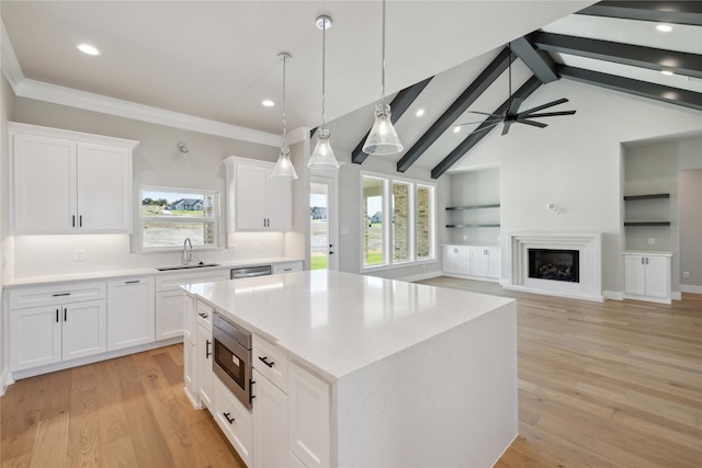 kitchen with pendant lighting, sink, stainless steel appliances, white cabinets, and a kitchen island