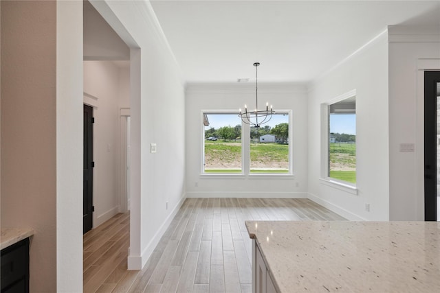 unfurnished dining area featuring ornamental molding, light wood-type flooring, and a notable chandelier