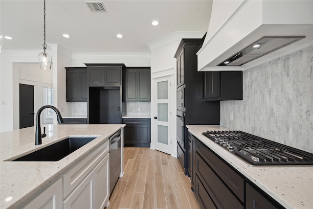 kitchen featuring sink, custom exhaust hood, white cabinetry, appliances with stainless steel finishes, and light stone countertops