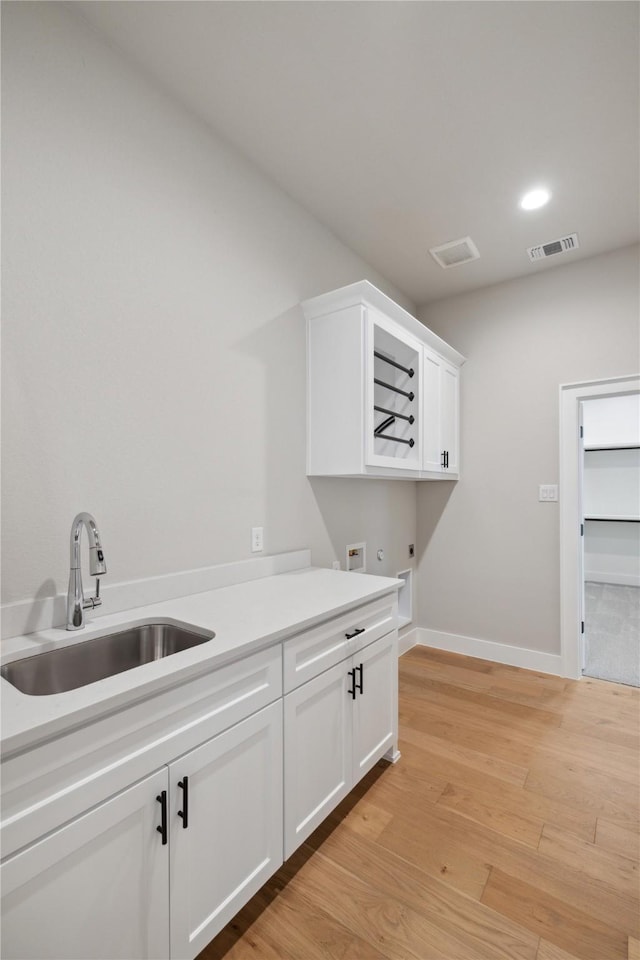 laundry room featuring sink, cabinets, light hardwood / wood-style flooring, washer hookup, and hookup for an electric dryer