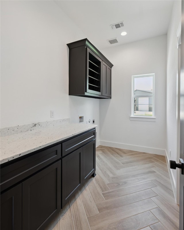 laundry room with cabinets, light parquet flooring, and hookup for a washing machine