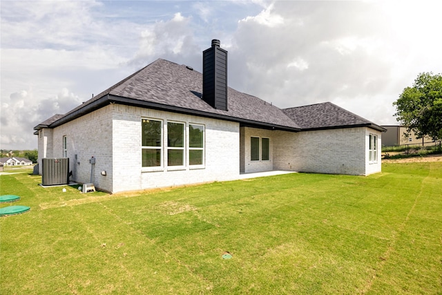 rear view of property with a lawn and central air condition unit