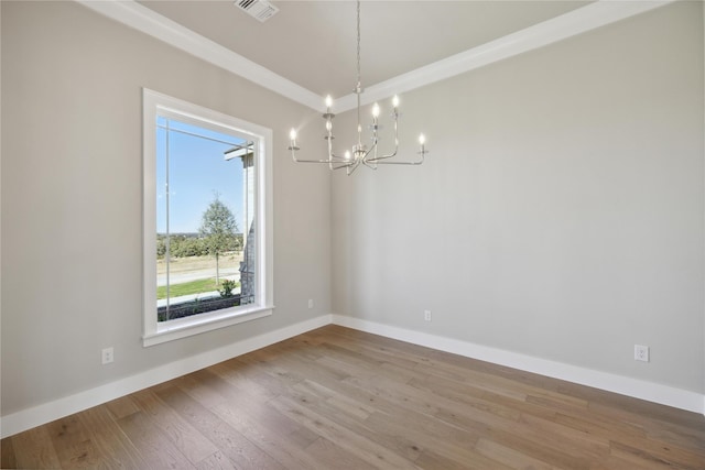 spare room with a notable chandelier, ornamental molding, and light wood-type flooring