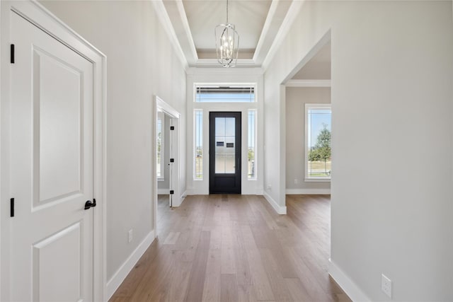 entryway with ornamental molding, light hardwood / wood-style flooring, and a notable chandelier