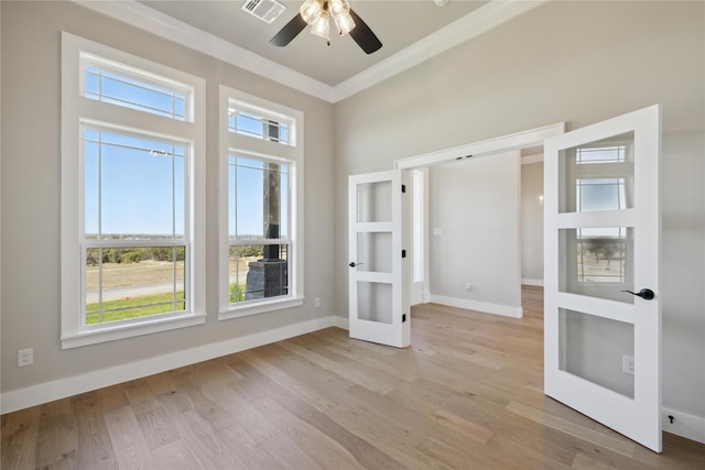 empty room with crown molding, ceiling fan, light hardwood / wood-style flooring, and french doors