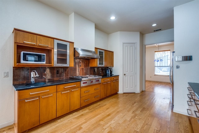 2002 Moser Ave, Dallas, TX 75206 - kitchen with wall chimney exhaust hood, sink, light hardwood / wood-style flooring, appliances with stainless steel finishes, and backsplash