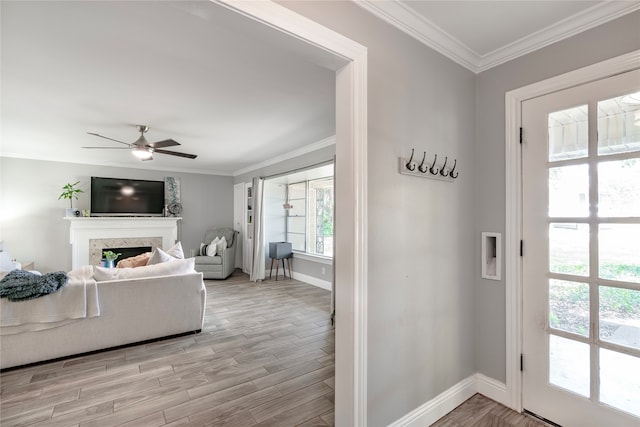 interior space featuring ceiling fan, ornamental molding, a premium fireplace, and light hardwood / wood-style floors