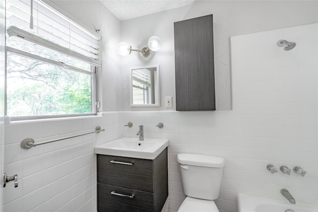 full bathroom featuring toilet, a textured ceiling, tile walls, vanity, and shower / washtub combination