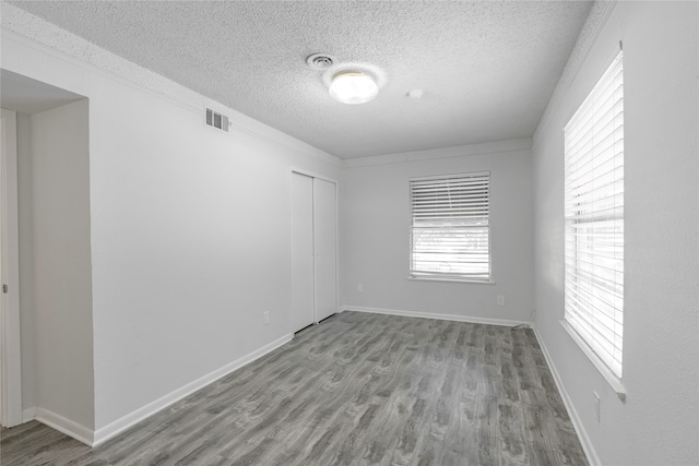 empty room featuring a textured ceiling and light hardwood / wood-style floors