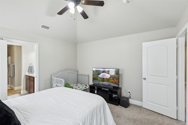 bedroom featuring ceiling fan, light colored carpet, connected bathroom, and vaulted ceiling