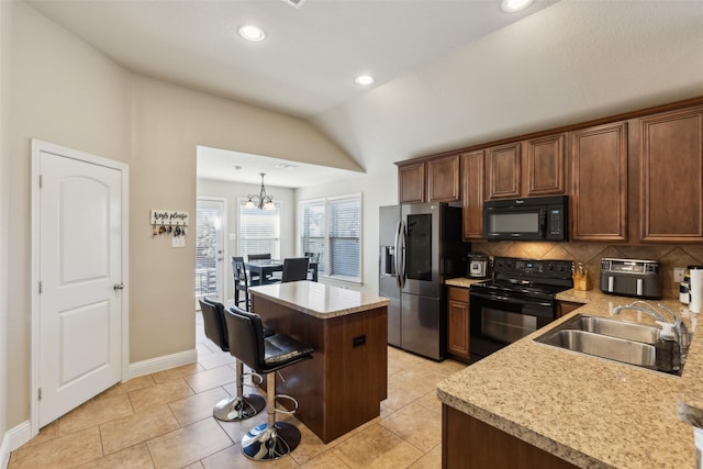 kitchen featuring lofted ceiling, sink, backsplash, black appliances, and a kitchen island