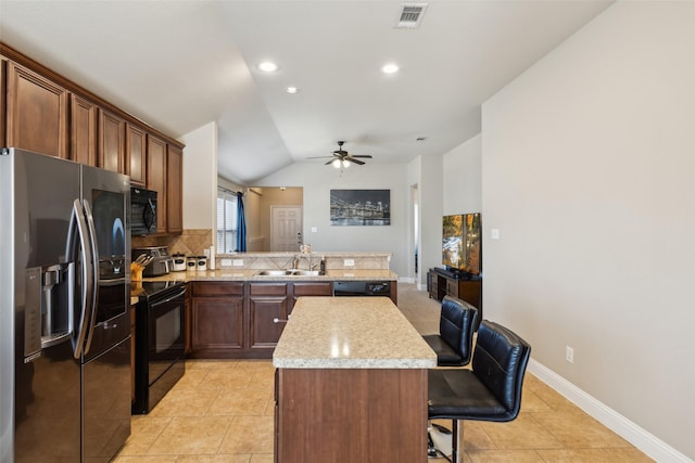 kitchen with a breakfast bar, sink, vaulted ceiling, kitchen peninsula, and black appliances