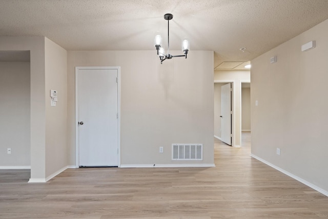 unfurnished dining area featuring a textured ceiling and light hardwood / wood-style flooring