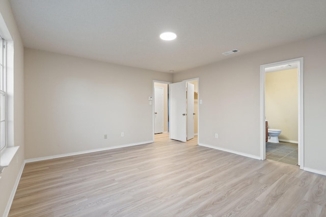 unfurnished bedroom with light hardwood / wood-style flooring and ensuite bathroom